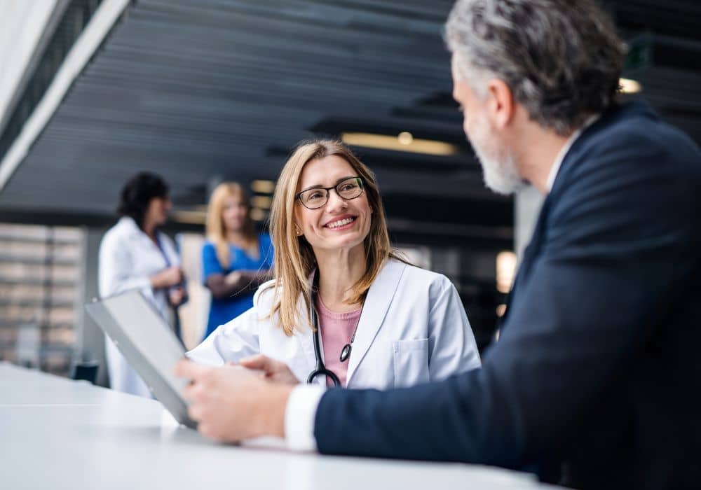 Healthcare professional talking to a man in a suit looking at documents