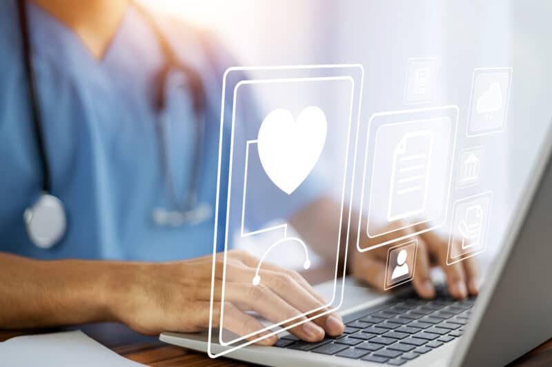 Doctor using a computer with icons of documents, people and health around the image