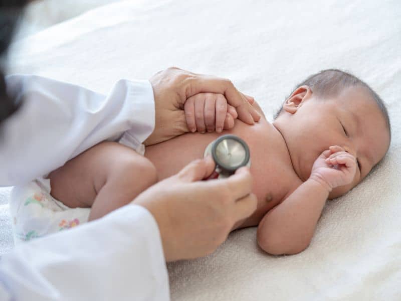 A healthcare professional using a stethoscope on a baby